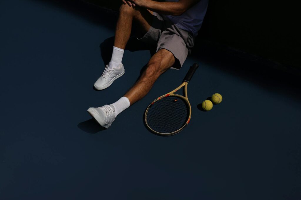 A tennis player resting on the court with racket and balls, in São Paulo, Brazil.